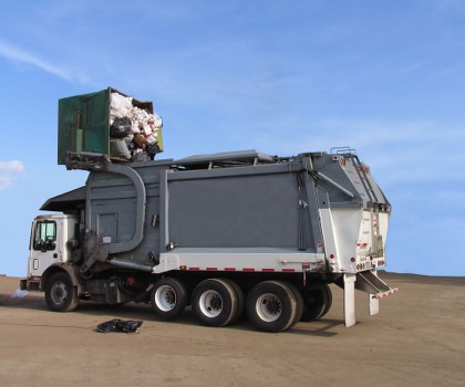 Skip hire truck beside a placed skip on paved site